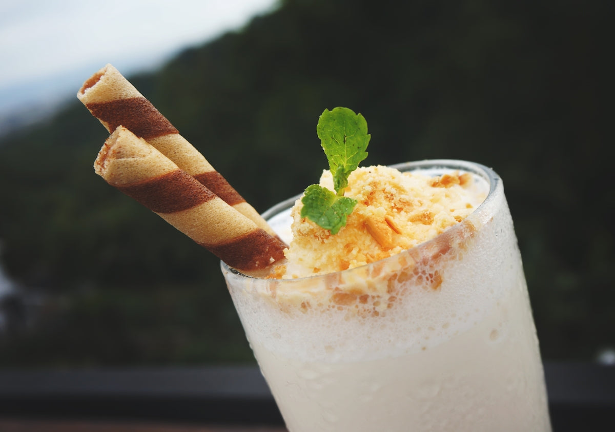 A tall glass with a drink and two straws in it